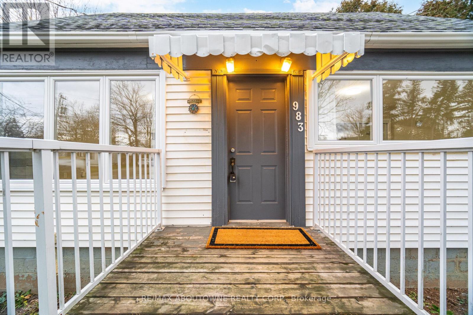 A house numbered 983 is shown with a wooden porch and a grey door.