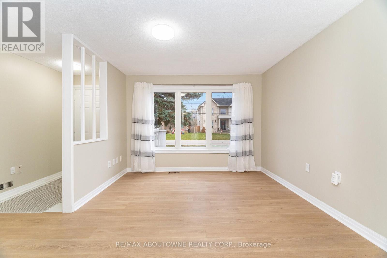 A spacious room with a view of a residential area through the window.