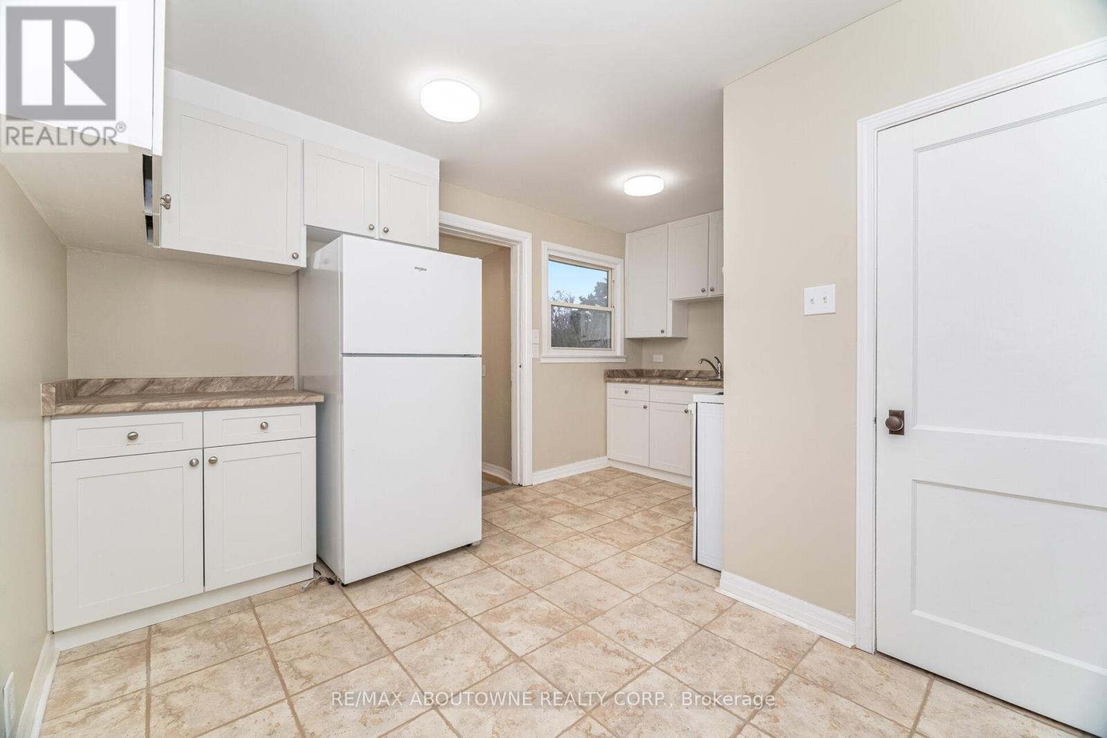 A kitchen with white cabinets and a refrigerator.