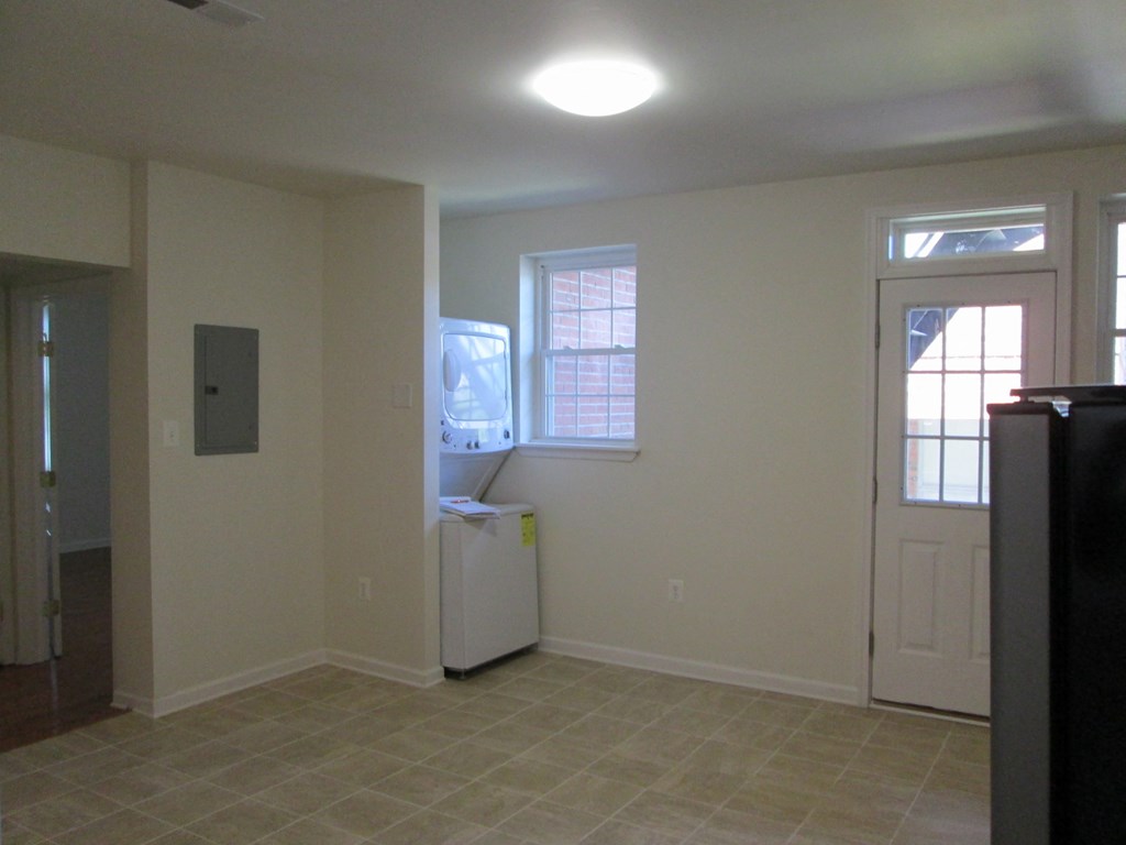 an empty living room with a fridge and a window