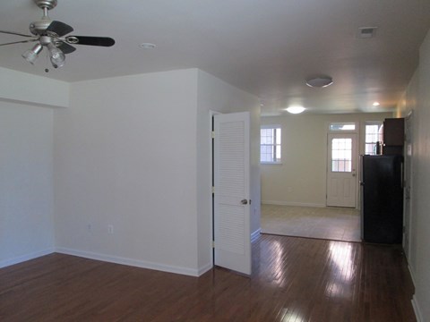an empty living room with white walls and a ceiling fan