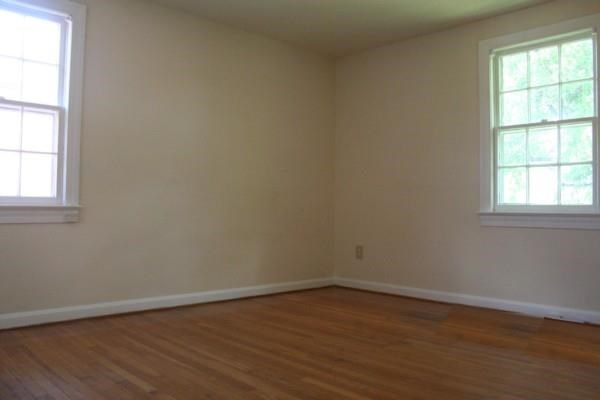 an empty room with a wooden floor and two windows