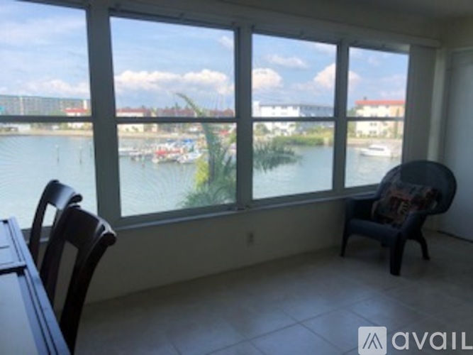 A room with a table and chairs and a view of a river with boats.