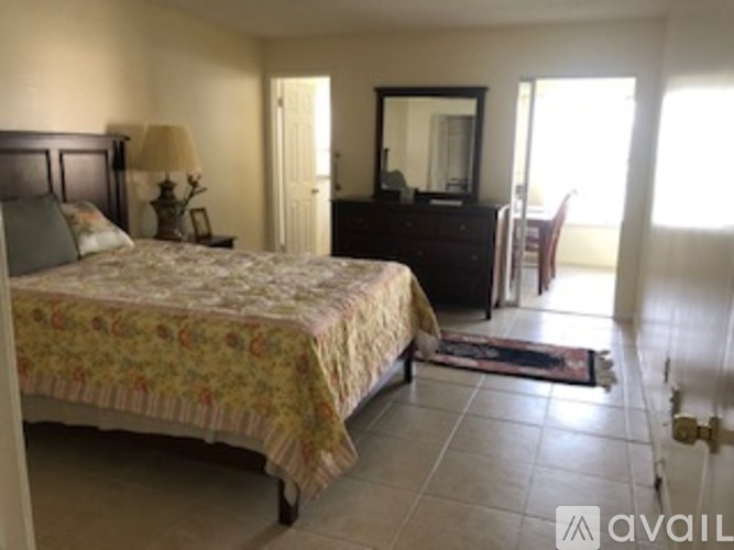 A bedroom with a bed, dresser, mirror, and chair.