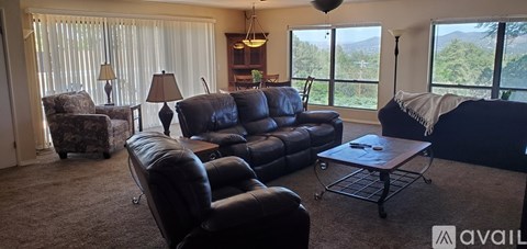 A living room with a black leather couch and a coffee table.