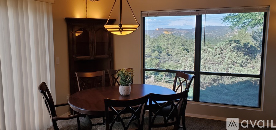 A dining room with a table and chairs and a view of the outdoors.