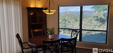 A dining room with a table and chairs and a view of the outdoors.