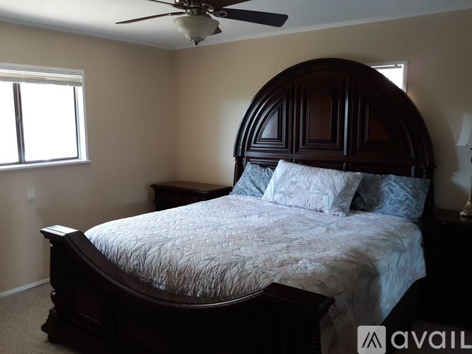 A bedroom with a large bed and a ceiling fan.