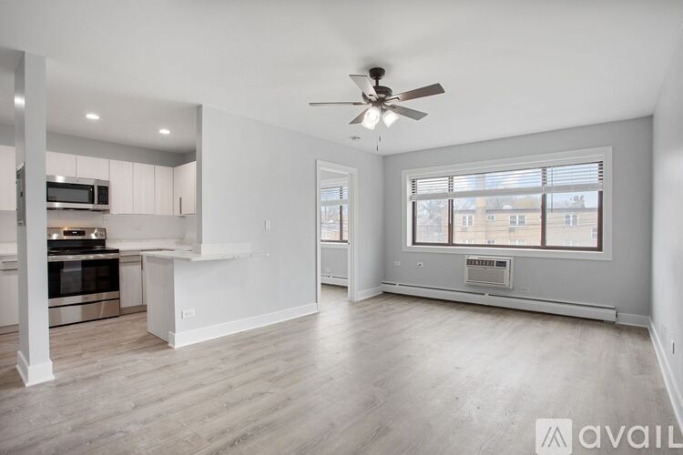 A spacious living room with a ceiling fan and a view of a building outside the window.