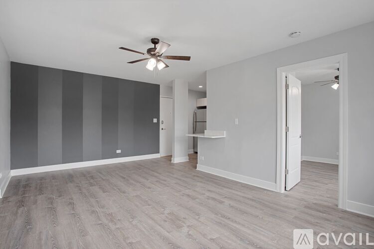 A room with a ceiling fan and light fixture, and a wall with a striped pattern.
