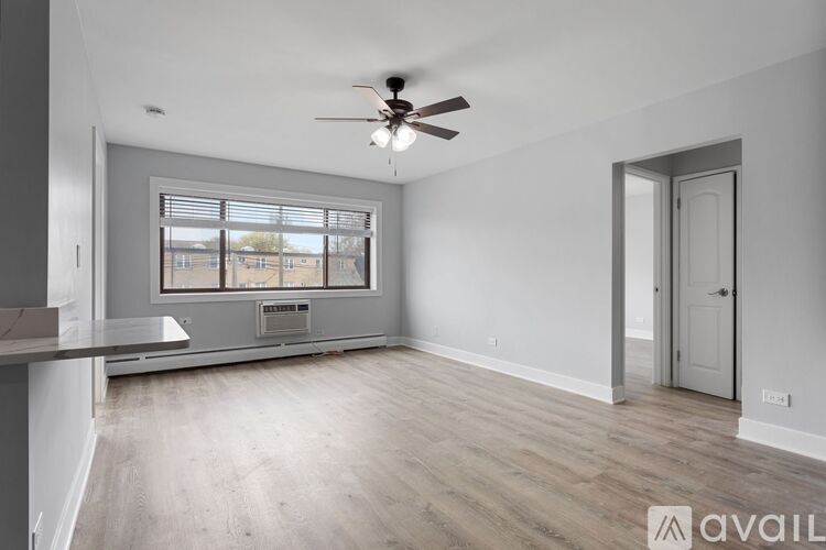 A spacious room with a ceiling fan and a window overlooking a building.