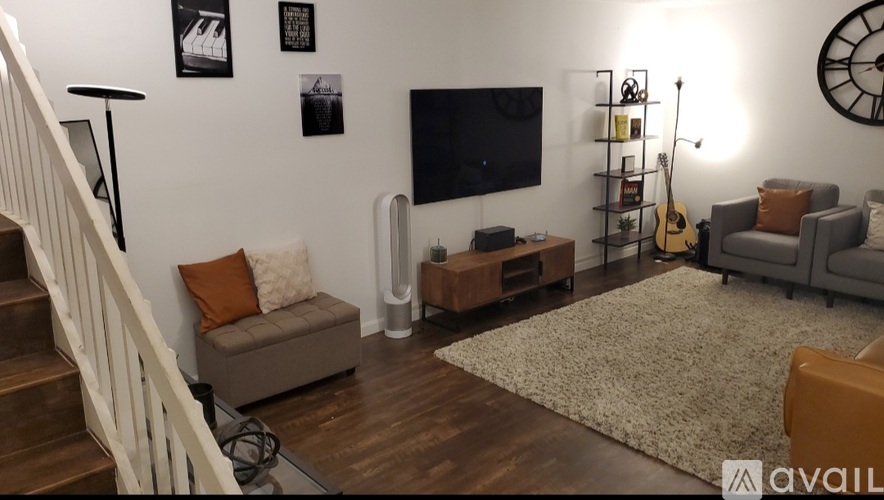 A living room with a staircase on the left and a couch with a throw pillow on the right.