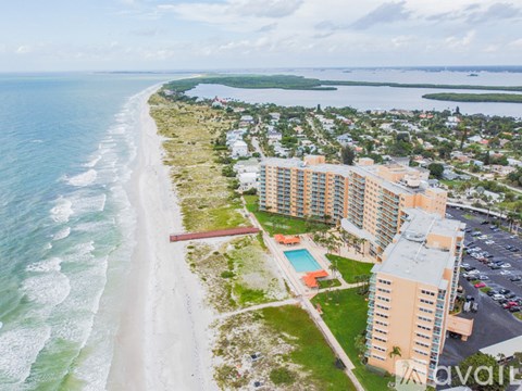 A beachfront hotel with a swimming pool and a view of the ocean.