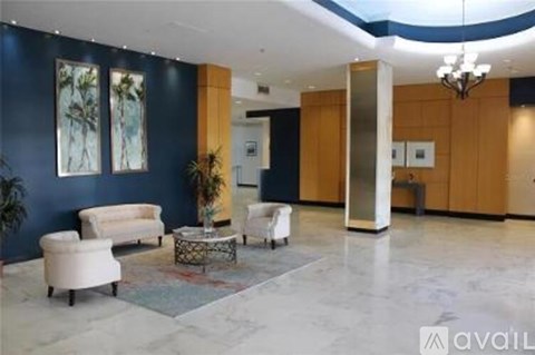 A spacious lobby with a white sofa, a coffee table, and a large painting on the wall.