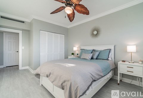 A bedroom with a bed, a ceiling fan, and a nightstand with a lamp.