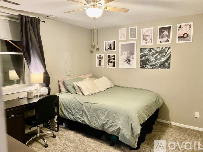 A bedroom with a bed, desk, chair, and pictures on the wall.