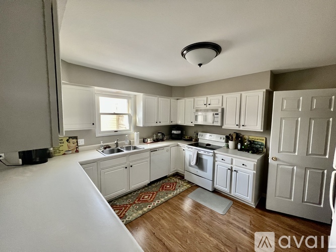 A kitchen with white cabinets and a wooden floor.