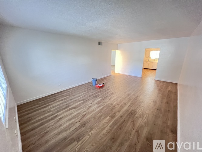 A room with wooden flooring and a window on the left side.