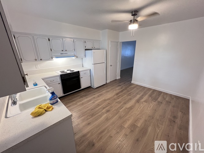 A kitchen with white cabinets and a wooden floor.