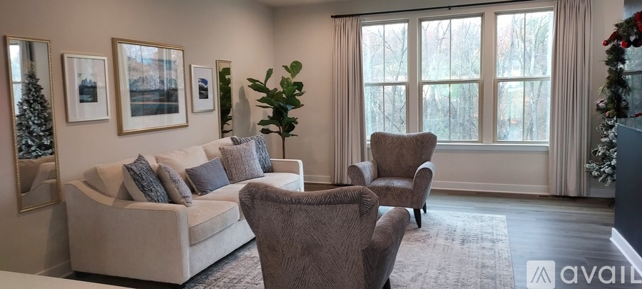 A living room with a couch, chairs, and a Christmas tree.