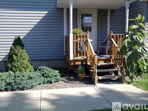A house with a porch and a small tree.