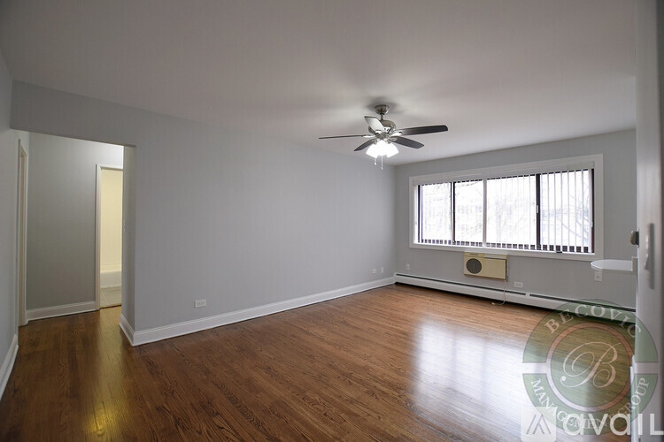 A spacious room with a ceiling fan and wooden flooring.