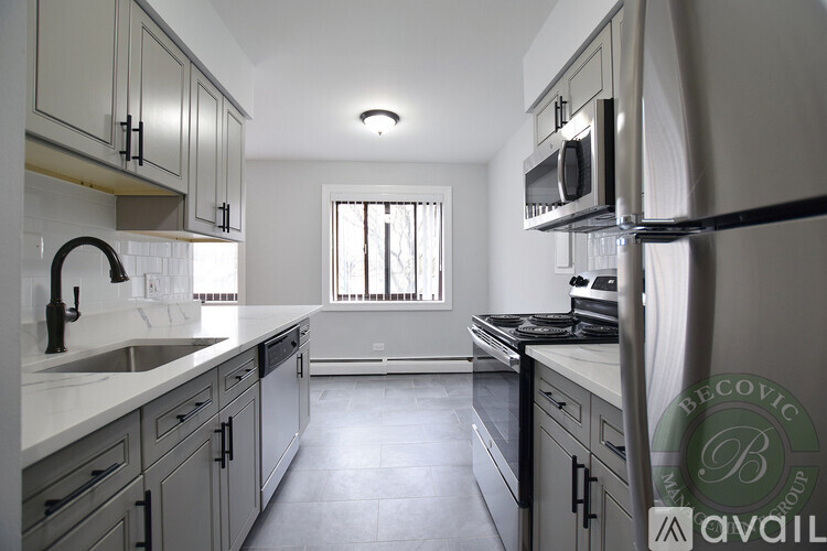 A kitchen with a white counter top and grey cabinets.