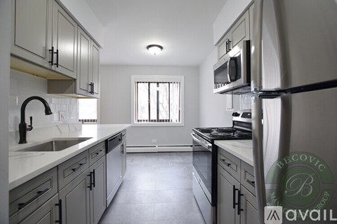 A kitchen with a white counter top and grey cabinets.