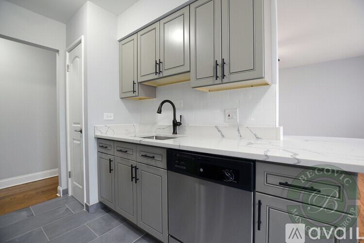 A kitchen with a marble countertop and grey cabinets.
