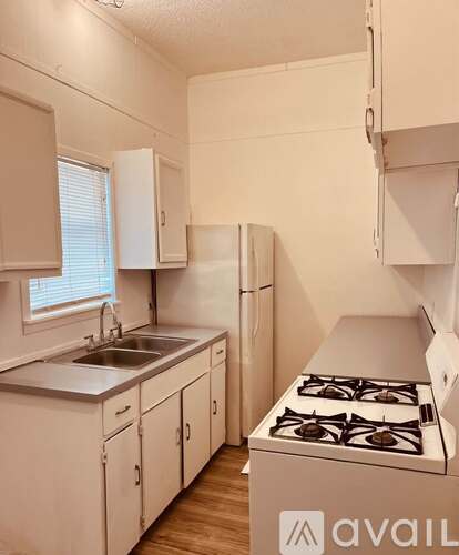 A small kitchen with a stove, sink, and cabinets.