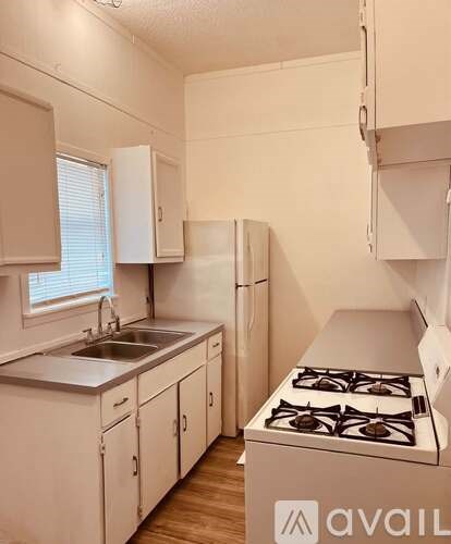 A small kitchen with a stove, sink, and cabinets.