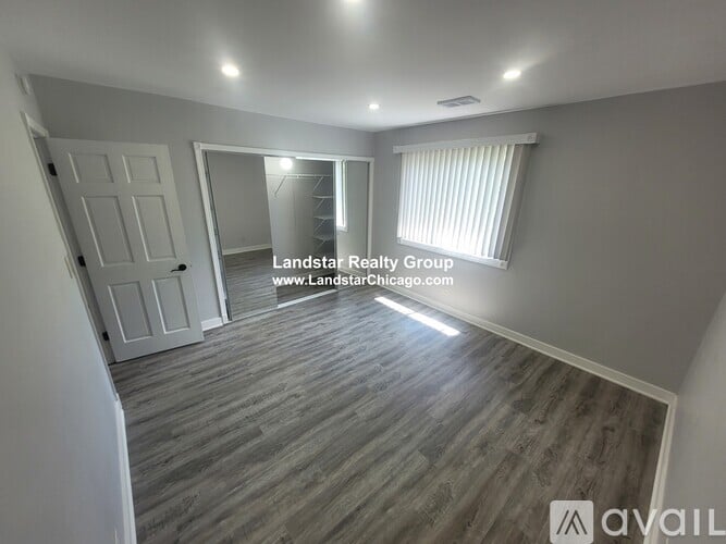 A spacious room with wooden flooring and a white door.