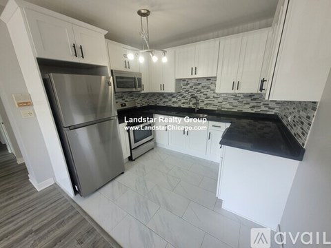 A kitchen with a refrigerator, microwave, and stove top oven.