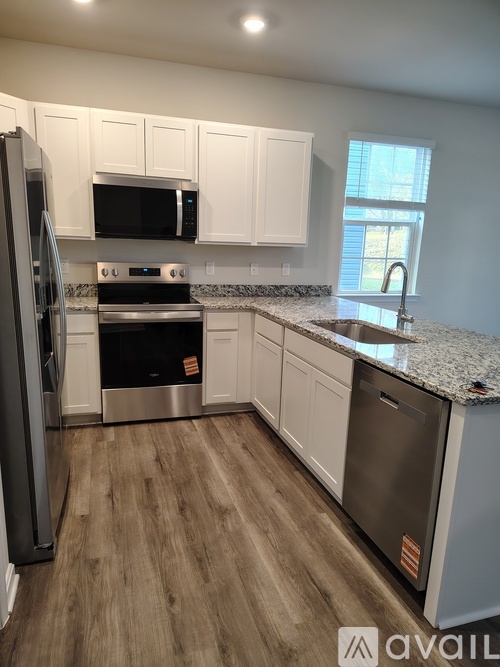 A kitchen with a refrigerator, microwave, oven, and cabinets.