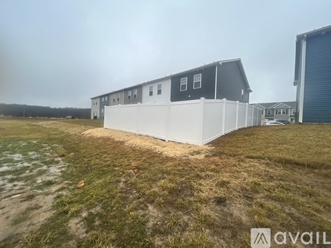 A large white building with a grey roof is situated in a grassy field.