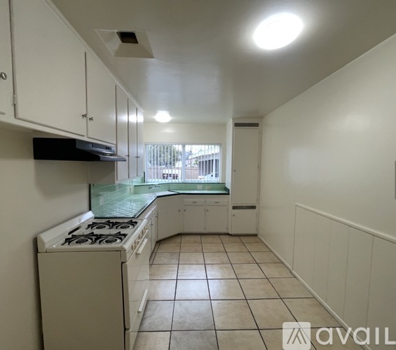 A kitchen with white cabinets and a stove top oven.