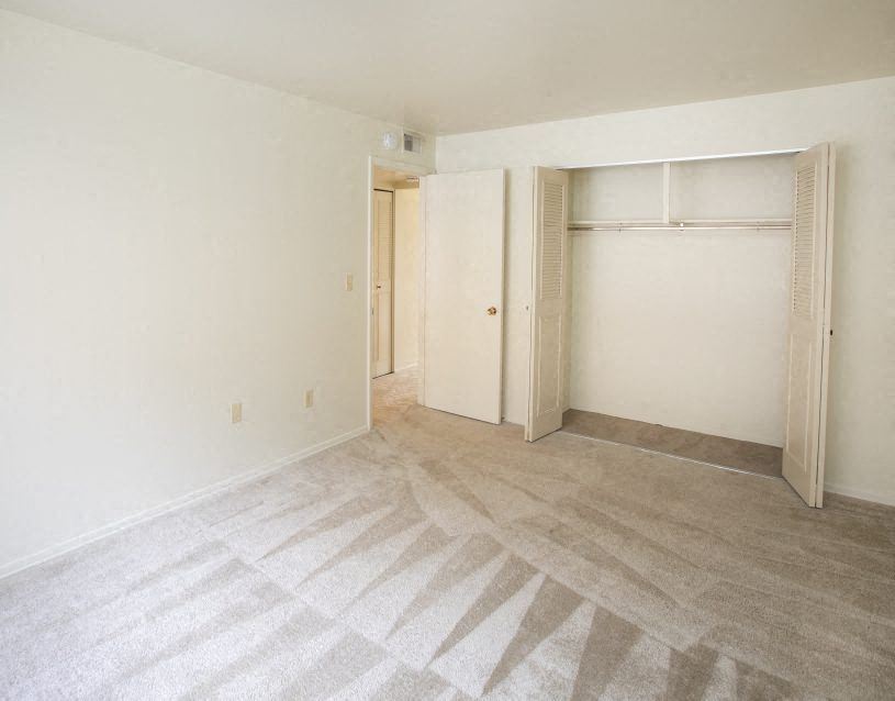 an empty living room with white walls and a closet