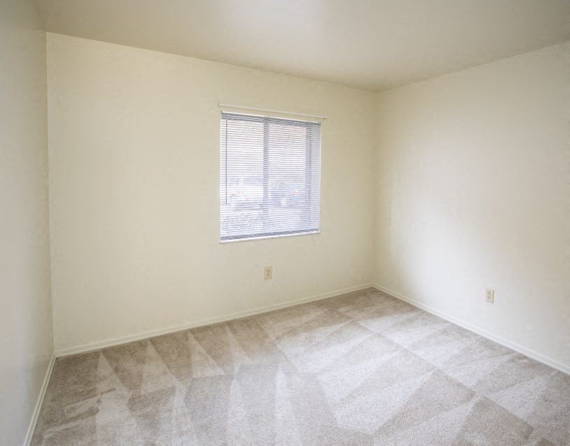 an empty room with white walls and a window