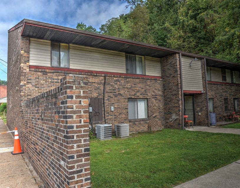 the side of a brick building with a yard and a cone