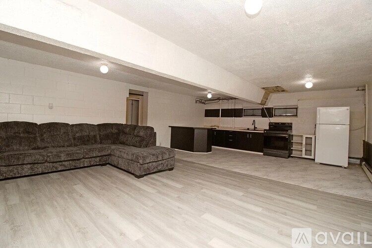 A living room with a grey couch and a kitchen area in the background.