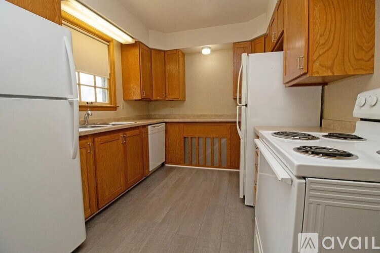 A kitchen with white appliances and wooden cabinets.