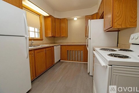 A kitchen with white appliances and wooden cabinets.