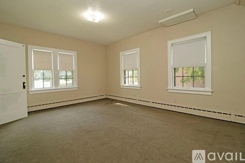 A room with a carpeted floor, two windows, and a door.