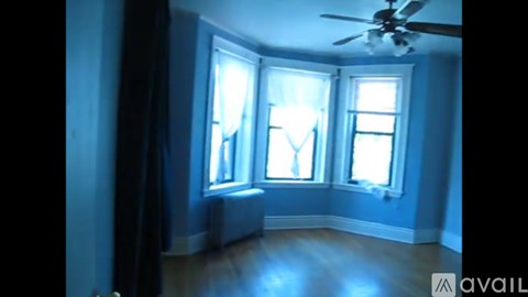 A room with a ceiling fan and three windows.