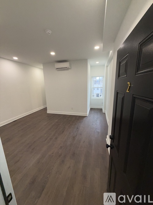 A room with a black door and wooden flooring.