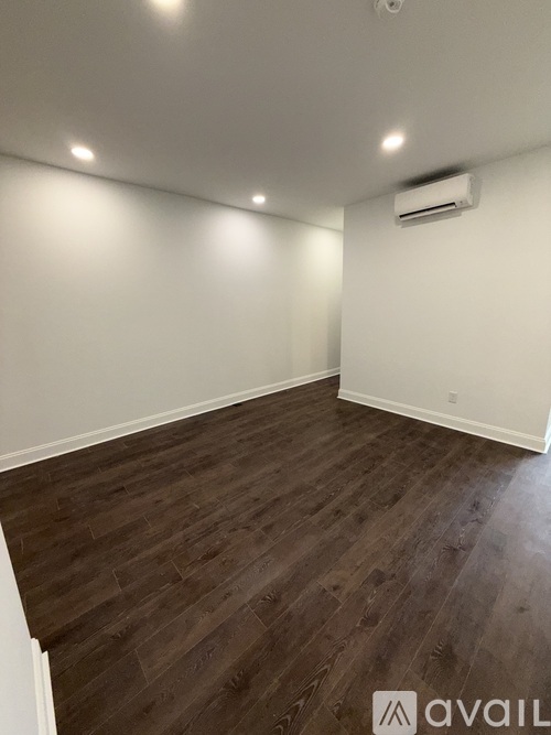 A room with wooden flooring and an air conditioner mounted on the wall.