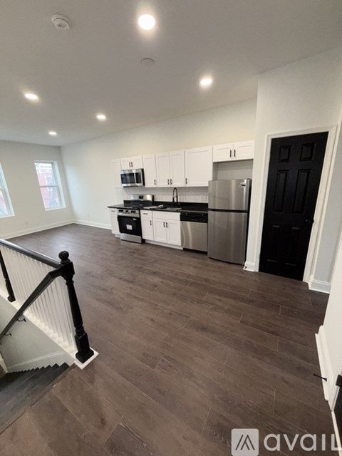 A kitchen with white cabinets and a black door.