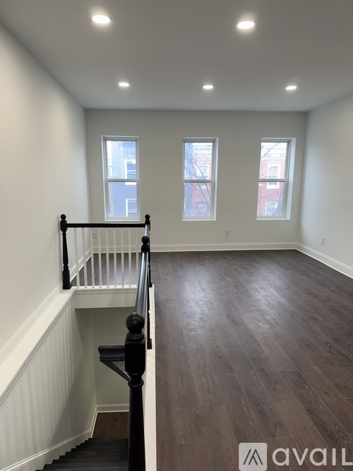 A room with wooden floors and a staircase leading to the second floor.