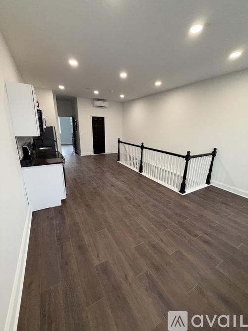 A spacious room with wooden flooring and white walls.