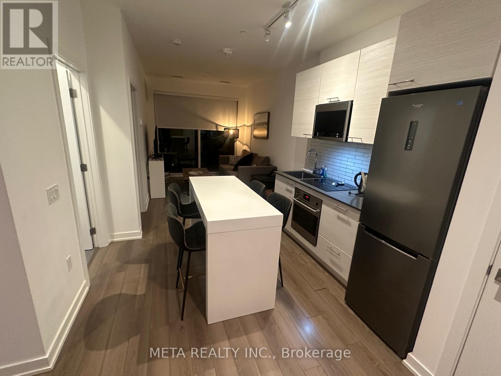 A kitchen with a white island and black chairs.